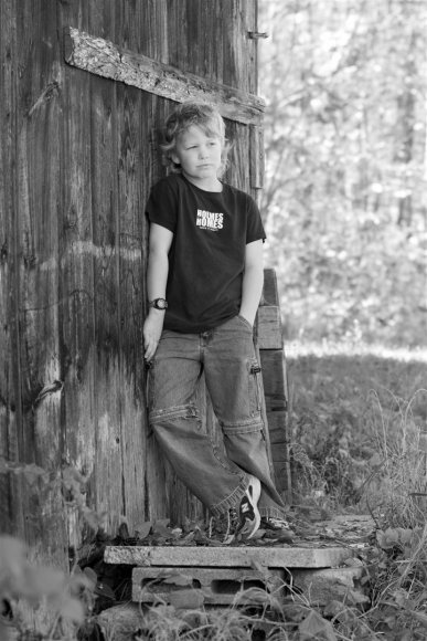 Young man beside an old barn.